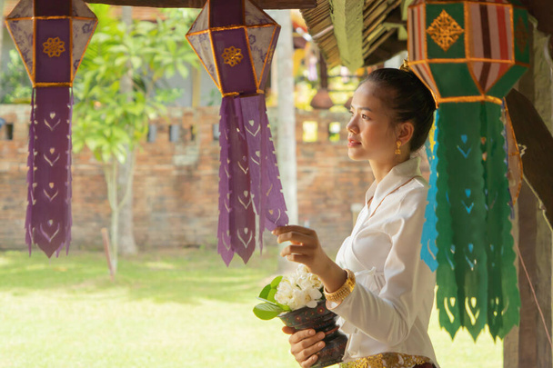 Portré mosolygós ázsiai Shan nő lány, Tai Yai, észak-thai emberek hagyományos Lanna ruhák kezében virágok Wat Ton Kwen templom, Lanna lámpások dekoráció. Kultúra életmód. - Fotó, kép