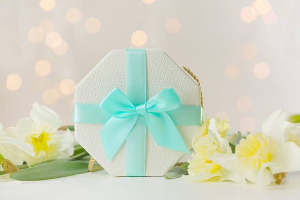 Caja de regalo y hermosas flores en la mesa contra luces borrosas - Foto, imagen