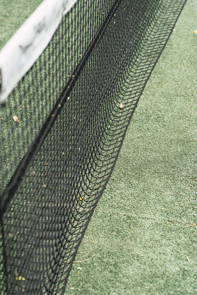A vertical selective focus shot of the dividing net in a tennis field on a sunny day - Photo, Image