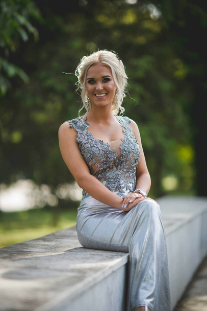 A blonde lady in a silver evening dress posing - Photo, Image