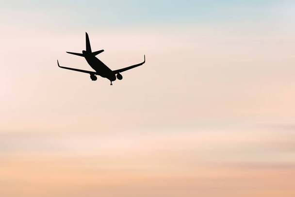 Egy utas repülési történet sziluettje, turistákkal, akik a reptéren landoltak. Repülőgép leszállt napnyugtakor. az utasszállító repülőgép hajnalban landol a repülőtéri kifutópályán. - Fotó, kép