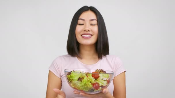 Alegre senhora japonesa segurando tigela de salada Gesturing Thumbs-Up, fundo branco - Filmagem, Vídeo