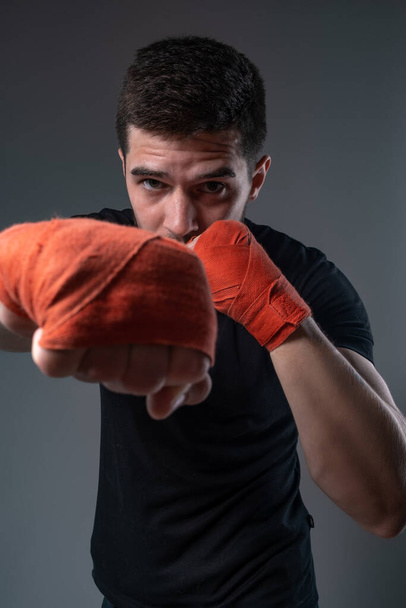 Sportsman throwing right straight punch with hand in wrist wraps - Photo, Image