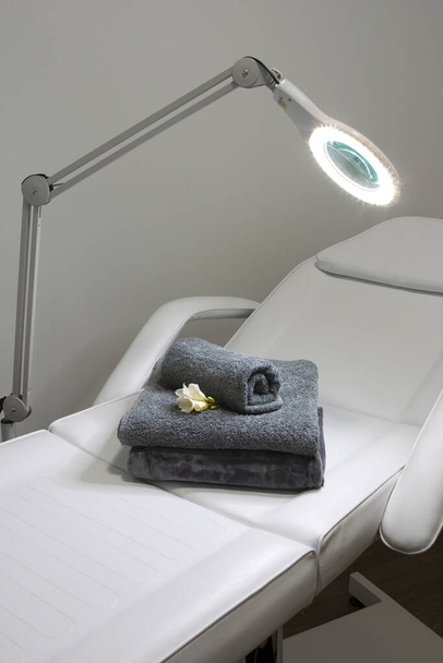 A vertical shot of soft towels and a single flower on a massage bed indoors - Fotoğraf, Görsel