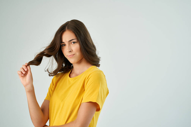 pretty brunette holding hair hairstyle fashion yellow t-shirt studio - Photo, image