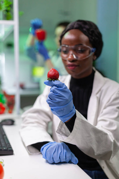 Científico químico mirando fresa con líquido orgánico examinando prueba de ADN - Foto, Imagen