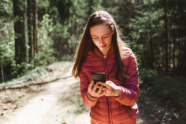 One 13s girl making a video call to her friend in the forest, Online communication concept.Nice sunny summer or spring day. - Photo, Image