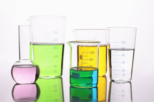 laboratóriumi üvegáruk, fehér alapon színes folyadékkal töltve - Fotó, kép