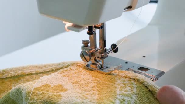 De naald van de naaimachine beweegt snel op en neer. Vrouwelijke handen stiksel witte stof op professionele productie machine op de werkplek. - Video