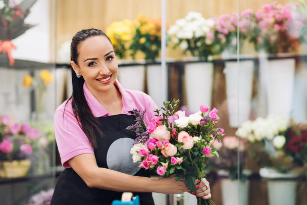 Портрет молодой флористки с красивым праздничным букетом в руках. Цветочный магазин, букет цветов - Фото, изображение