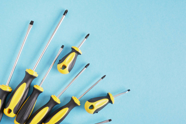 Screwdriver set on a blue background top view copy space many screwdrivers with black and yellow handles - Foto, Imagen