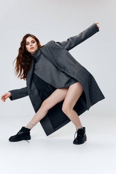woman in a sweater coat and boots posing on a light background indoors - Foto, afbeelding