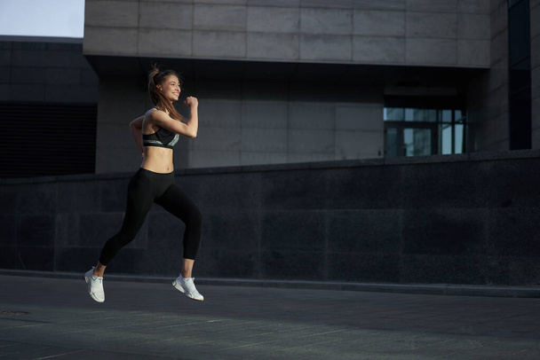 Woman running urban city street background Active sporty caucasian female morning workout Healthy lifestyle concept. Athletic person dressed sportswear do exercises Dark tone mood Corporate building - Foto, Bild
