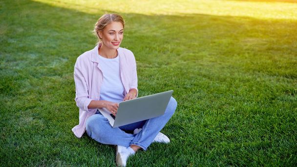 Businesswoman sitting grass summer park using laptop Business persone working remote. Outdoors Successful european caucasian woman freelancer make video call teacher study work online lessons  - Photo, Image