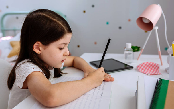 Дівчина навчається вдома з маскою на столі
 - Фото, зображення