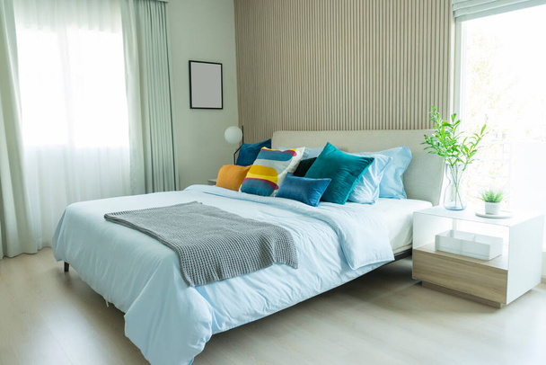 Wnętrze białej, żółtej i niebieskiej poduszki w przytulnej nowoczesnej sypialni. - Zdjęcie, obraz