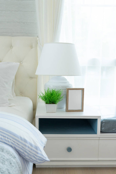 Современный интерьер спальни с синими и белыми подушками с лампой для чтения на тумбочке. - Фото, изображение