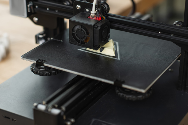 крупным планом 3D принтера, создающего пластиковую модель в современном офисе - Фото, изображение