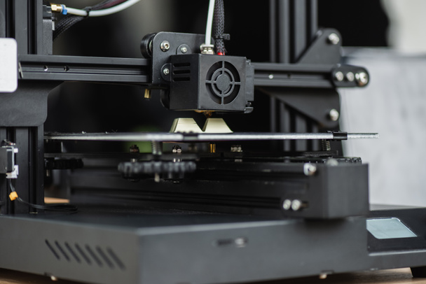 Nahaufnahme des 3D-Druckers zur Erstellung eines Plastikmodells auf unscharfem Hintergrund - Foto, Bild