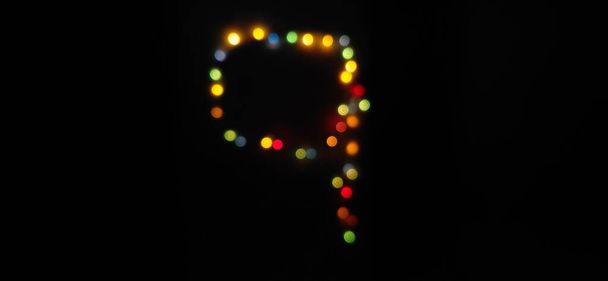 Closeup de número nove (9) feito com luzes seriais bokeh borradas multicoloridas em um fundo preto isolado com espaço de cópia e foco seletivo. - Foto, Imagem