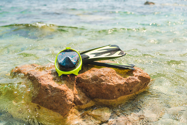 海の水のコピースペースの岩でフリッパー付きシュノーケリングマスク - 写真・画像