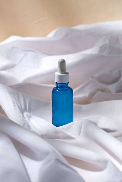 bottle of serum on white sheet - Φωτογραφία, εικόνα