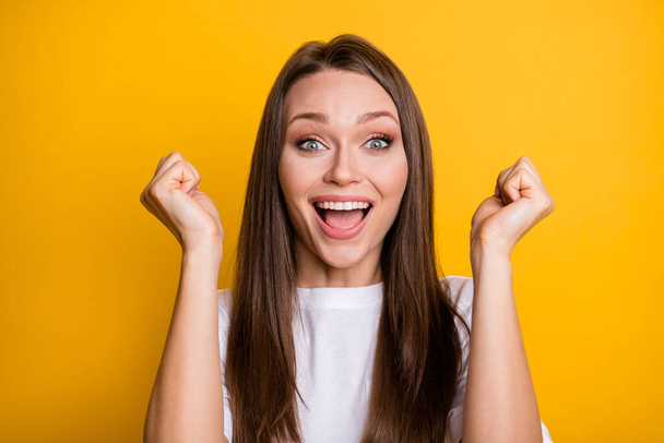 Photo portrait of excited girl with raised fists isolated on bright yellow colored background - Foto, Bild