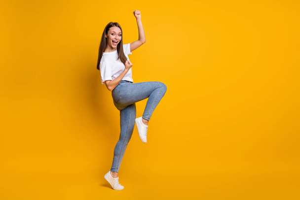 Photo portrait full body view of excited woman with raised fists on one leg celebrating isolated on vivid yellow colored background - Photo, image