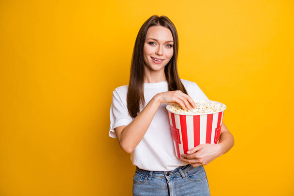 Photo portrait of pretty girl with brown straight hair eating pop corn in cinema isolated vivid yellow color background - Fotoğraf, Görsel