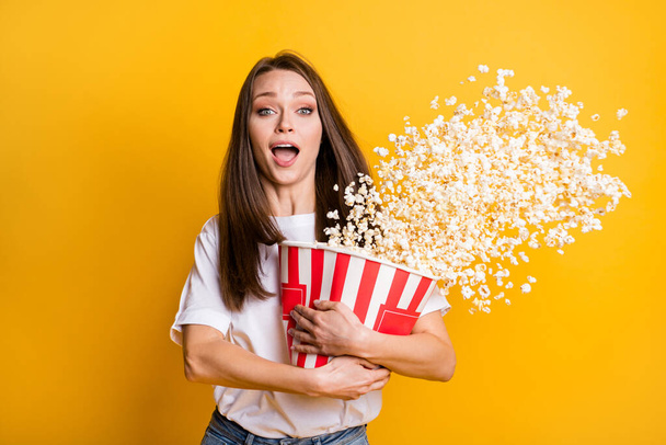 Photo portrait of excited girl throwing pop corn in air watching horror terrified afraid fear isolated vivid yellow color background - Zdjęcie, obraz