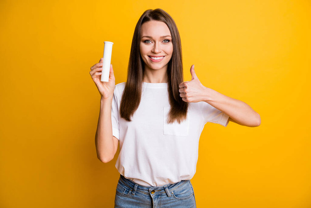 Photo portrait of pretty brunette girl showing like gesture with finger keeping bottle with vitamins isolated vivid yellow color background - Valokuva, kuva