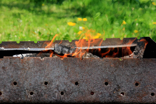 Empty grill grate and fire flame. Fire on charcoal for food grilling.Burning wood in the grill - Photo, image