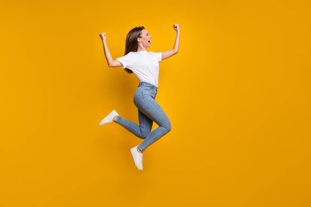 Full length body size photo of cheerful happy girl fan jumping high gesturing like winner shouting isolated bright yellow color background - Fotografie, Obrázek