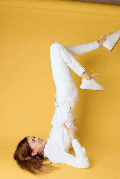 woman standing on her back with her legs raised upside down gold background - 写真・画像