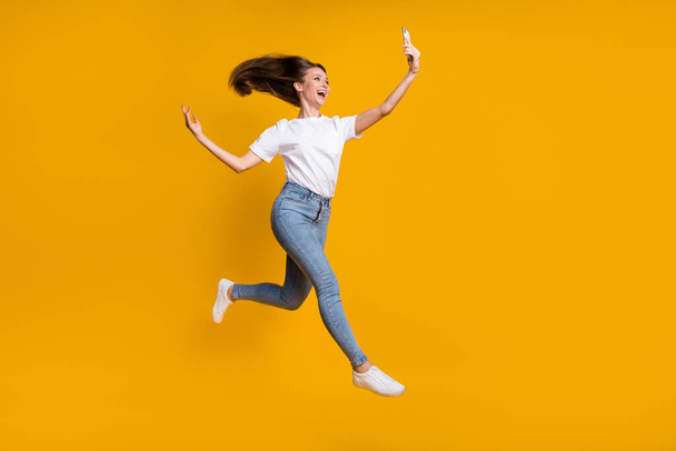 Full length body size photo of pretty woman taking selfie throwing hair jumping up isolated on bright yellow color background - Foto, immagini