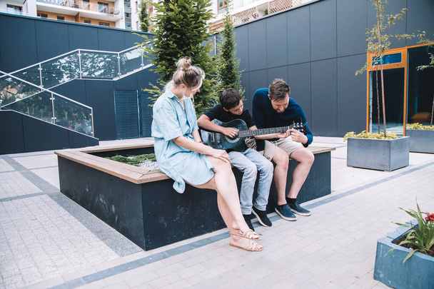  Son plays guitar for his parents in city square. Lifestyle. High quality photo - 写真・画像