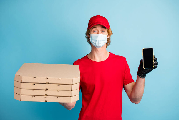 Photo of working guy hold pizzas show phone display wear safety facial mask isolated on blue color background - Foto, imagen