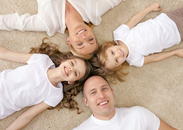 parents and two girls lying on floor at home - Фото, изображение
