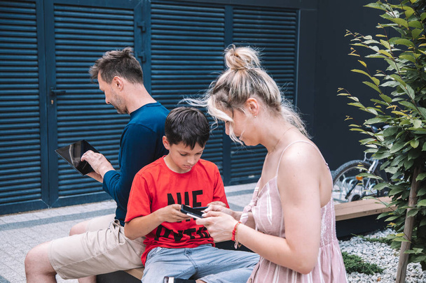  スマートフォンを使う現代の世代。家族は散歩にスマートフォンを使います。週末の夏の日に街。高品質の写真。ライフスタイル - 写真・画像