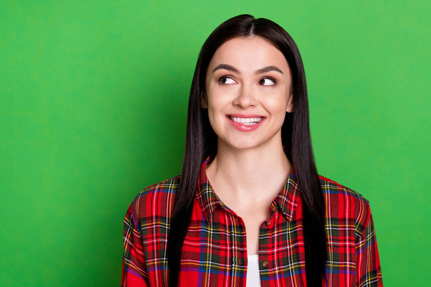 Portrait of attractive cheerful curious brunet girl biting lip copy space thinking isolated over bright green color background - Фото, изображение