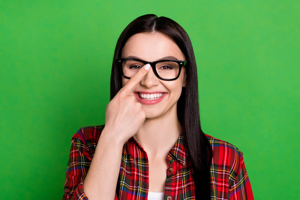 Photo of brunette smart young lady touch spectacles wear red shirt isolated on green color background - Zdjęcie, obraz