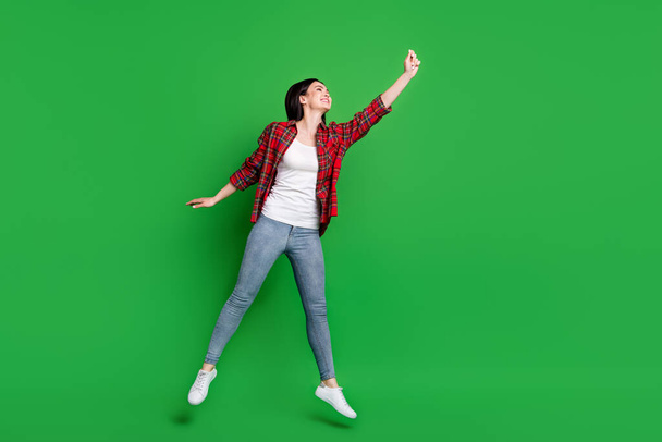 Full length photo of funky happy positive young woman jump up catch umbrella isolated on green color background - Foto, afbeelding