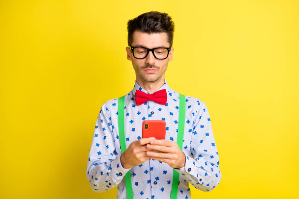 Photo of young serious man look read browse cellphone chat type sms isolated over yellow color background - Fotoğraf, Görsel