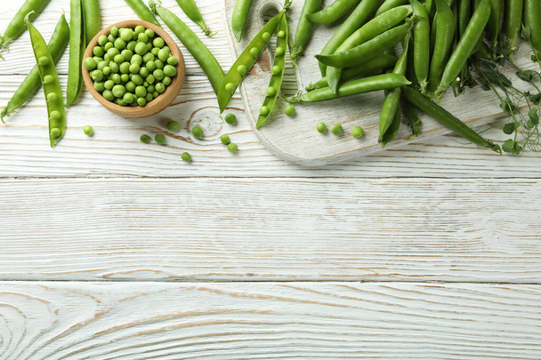 白い木製のテーブルの上に新鮮な緑のエンドウ豆 - 写真・画像