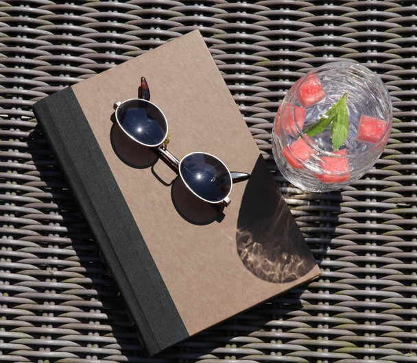 час відпочити на сонці з книгою і охолодженим склянкою кавуна наливають крижану воду
 - Фото, зображення