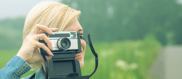 Beautiful blonde female photojournalist traveling and taking picture outdoors. Copy space for text or design. - Photo, Image