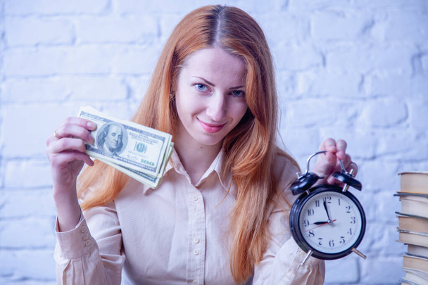 El tiempo es concepto de dinero. Retrato de una joven mujer de negocios en secreto sosteniendo un reloj y billetes de dólar. Imagen horizontal. - Foto, imagen