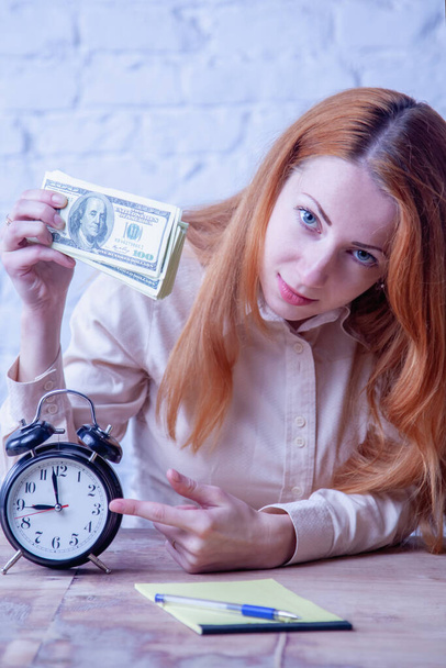 Время это денежная концепция. Портрет молодой предпринимательницы с часами и долларовыми купюрами.  - Фото, изображение