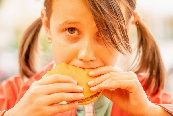 Portrét mladé krásné dívky jíst hovězí burger sendvič. Koncept rychlého občerstvení.  - Fotografie, Obrázek