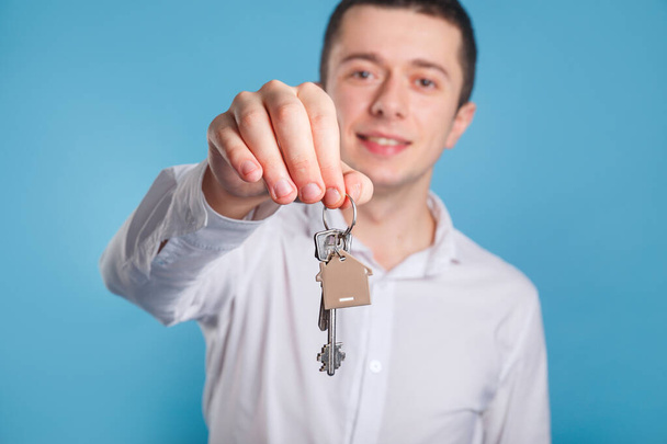 Агент бизнесмен с ключами. Держать ключи от дома на брелке в форме дома - Фото, изображение